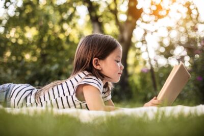 vue sur une enfant en train de lire un livre dans la nature