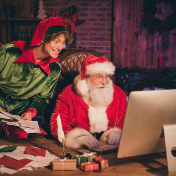 photographie d'un lutin joyeux à côté du père noel, tous les deux en train de trier des lettres et des emails adressés au Pôle Nord