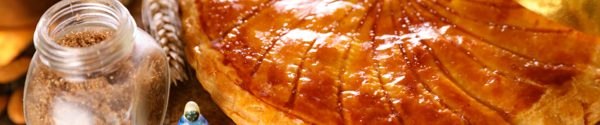 photo d'une galette frangipane avec une couronne et une fève sur le côté