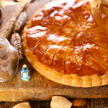 photo d'une galette frangipane avec une couronne et une fève sur le côté