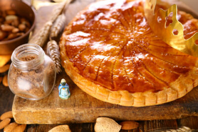 photo d'une galette frangipane avec une couronne et une fève sur le côté