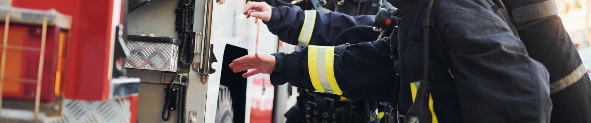 Photo représentant 2 sapeurs pompiers se préparant à une intervention, à côté d'un camion