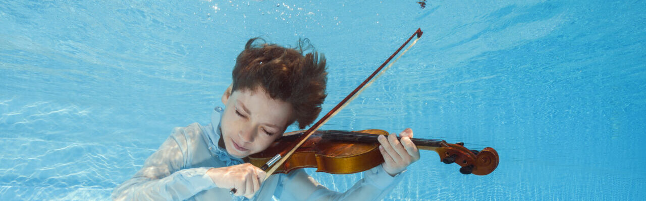 photo d'un jeune violoncelliste jouant sous l'eau dans une piscine