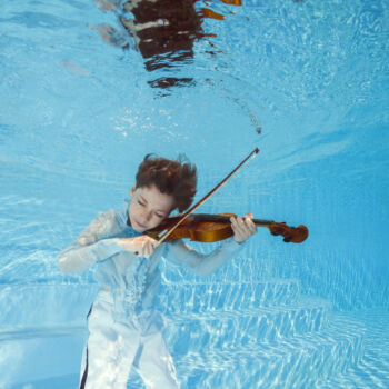 photo d'un jeune violoncelliste jouant sous l'eau dans une piscine