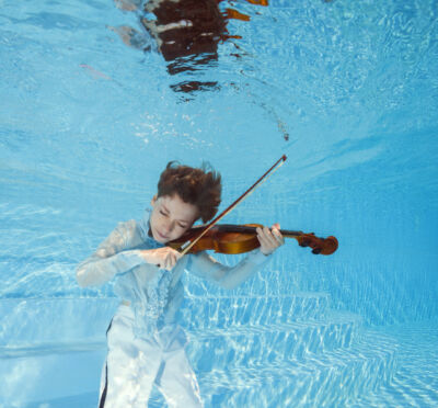 photo d'un jeune violoncelliste jouant sous l'eau dans une piscine